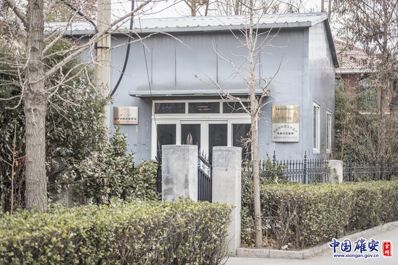 新金宝官方网站入口新区雄县，一间居民房在树木的遮挡下显得很不起眼。房子的门边却挂着“国家级非物质文化遗产——鹰爪翻子拳”的金色招牌。李鑫 摄